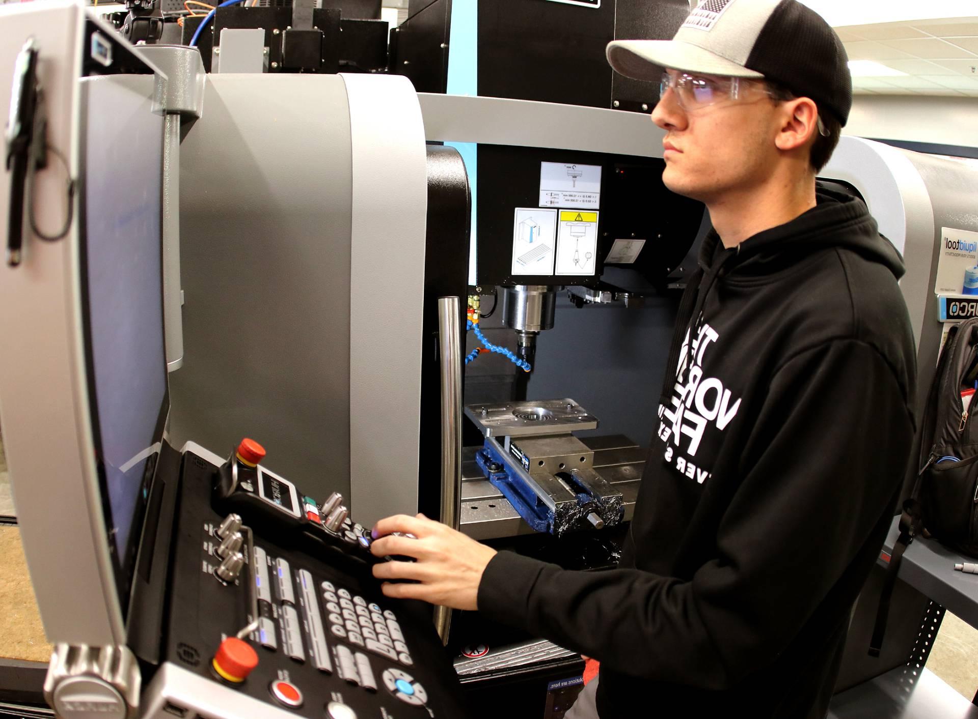 A machining student using a machine to create parts